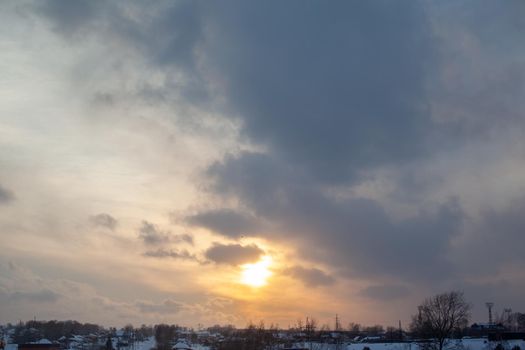The sun among the clouds over the winter city. Beautiful background. The sky and clouds are painted in different colors.
