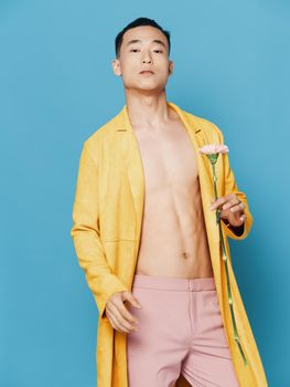 Korean man in a yellow coat with a flower in his hand and pink trousers. High quality photo