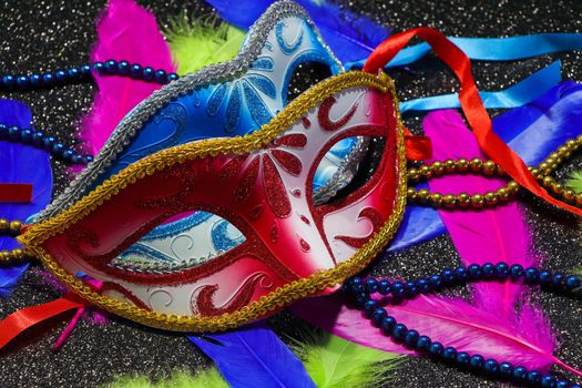 Mardi Gras carnival theme parade face masks with vibrant feathers and bead strings on textured black