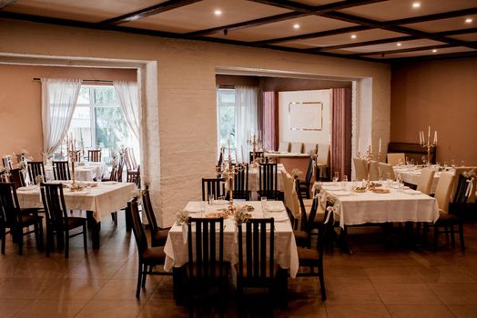 the presidium of the newlyweds in the banquet hall of the restaurant is decorated with candles and green plants, the general tone of the hall is beige