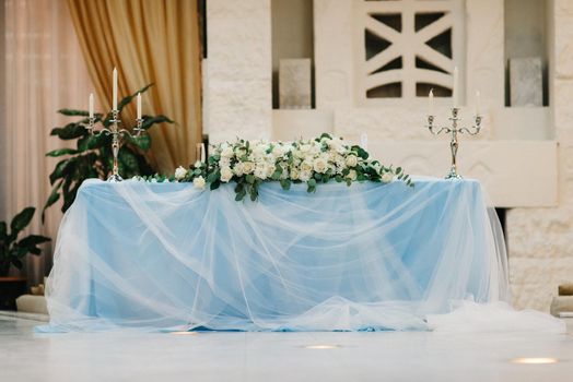 the presidium of the newlyweds in the banquet hall of the restaurant is decorated with candles and green plants, the general tone of the hall is beige