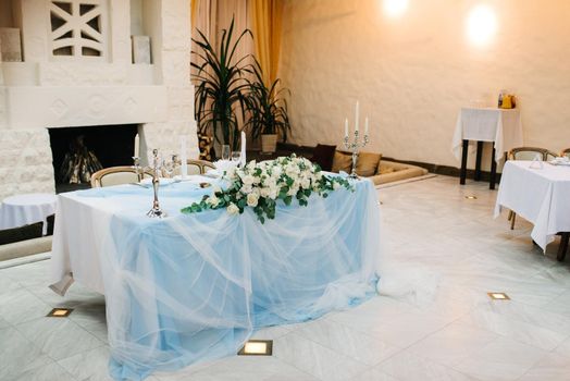 the presidium of the newlyweds in the banquet hall of the restaurant is decorated with candles and green plants, the general tone of the hall is beige