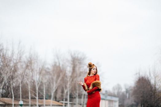 young girl with red hair in a bright red dress on the railway tracks of the station
