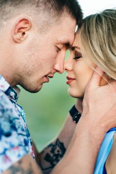 blonde girl with loose hair in a light blue dress and a guy in the light of sunset in nature