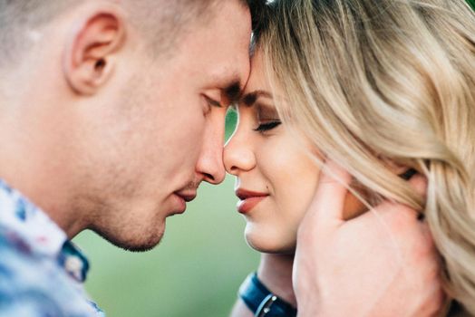 blonde girl with loose hair in a light blue dress and a guy in the light of sunset in nature