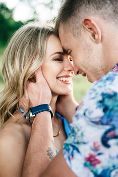 blonde girl with loose hair in a light blue dress and a guy in the light of sunset in nature