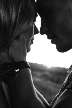 blonde girl with loose hair in a light blue dress and a guy in the light of sunset in nature