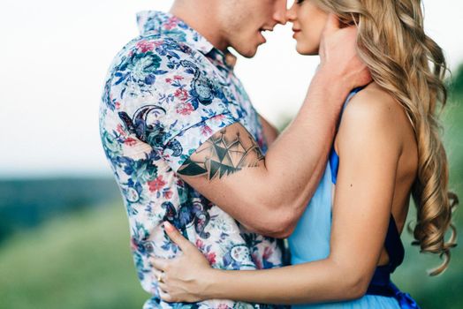 blonde girl with loose hair in a light blue dress and a guy in the light of sunset in nature