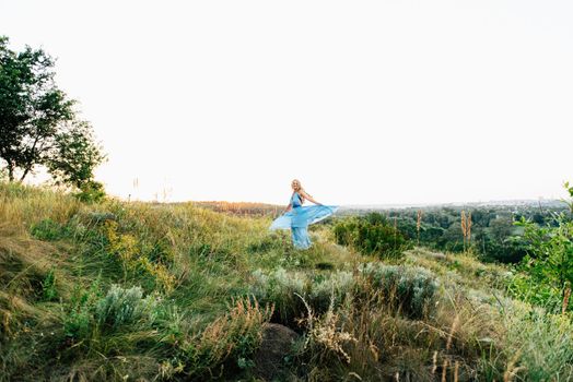 blonde girl with loose hair in a light blue dress and a guy in the light of sunset in nature