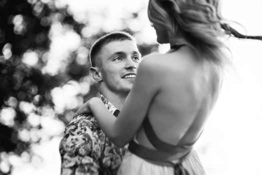 blonde girl with loose hair in a light blue dress and a guy in the light of sunset in nature