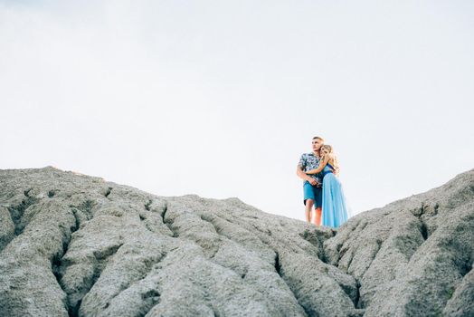 blonde girl in a light blue dress and a guy in a light shorts and short shert in a granite quarry