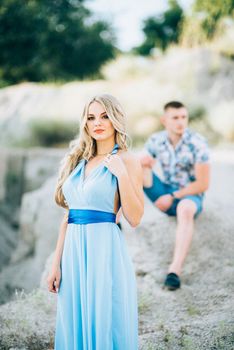 blonde girl in a light blue dress and a guy in a light shorts and short shert in a granite quarry