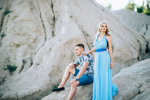 blonde girl in a light blue dress and a guy in a light shorts and short shert in a granite quarry