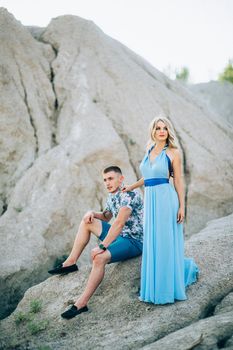 blonde girl in a light blue dress and a guy in a light shorts and short shert in a granite quarry