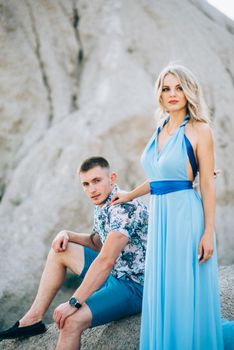 blonde girl in a light blue dress and a guy in a light shorts and short shert in a granite quarry