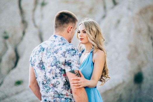 blonde girl in a light blue dress and a guy in a light shorts and short shert in a granite quarry