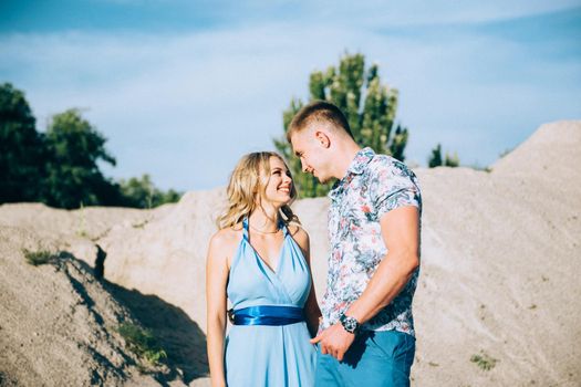 blonde girl in a light blue dress and a guy in a light shorts and short shert in a granite quarry