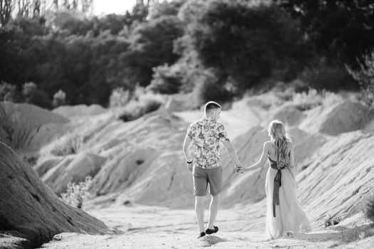 blonde girl in a light blue dress and a guy in a light shorts and short shert in a granite quarry