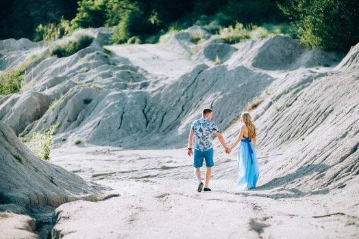 blonde girl in a light blue dress and a guy in a light shorts and short shert in a granite quarry