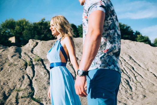 blonde girl in a light blue dress and a guy in a light shorts and short shert in a granite quarry