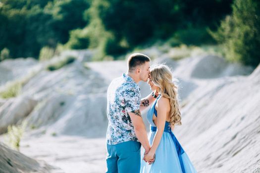 blonde girl in a light blue dress and a guy in a light shorts and short shert in a granite quarry