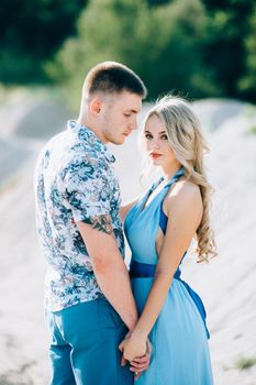 blonde girl in a light blue dress and a guy in a light shorts and short shert in a granite quarry