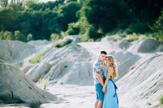 blonde girl in a light blue dress and a guy in a light shorts and short shert in a granite quarry