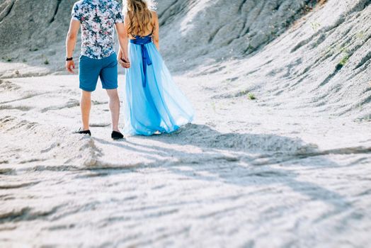 blonde girl in a light blue dress and a guy in a light shorts and short shert in a granite quarry