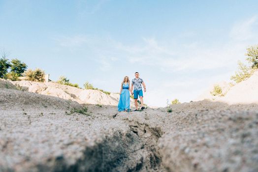 blonde girl in a light blue dress and a guy in a light shorts and short shert in a granite quarry