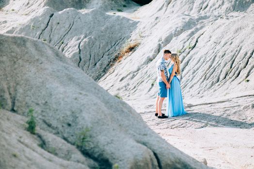 blonde girl in a light blue dress and a guy in a light shorts and short shert in a granite quarry