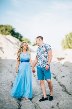 blonde girl in a light blue dress and a guy in a light shorts and short shert in a granite quarry