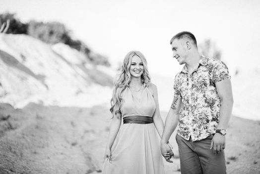 blonde girl in a light blue dress and a guy in a light shorts and short shert in a granite quarry