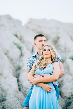 blonde girl in a light blue dress and a guy in a light shorts and short shert in a granite quarry