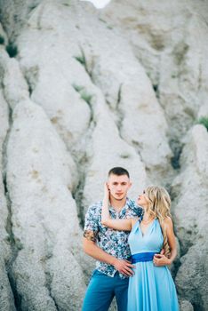 blonde girl in a light blue dress and a guy in a light shorts and short shert in a granite quarry