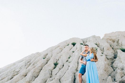 blonde girl in a light blue dress and a guy in a light shorts and short shert in a granite quarry