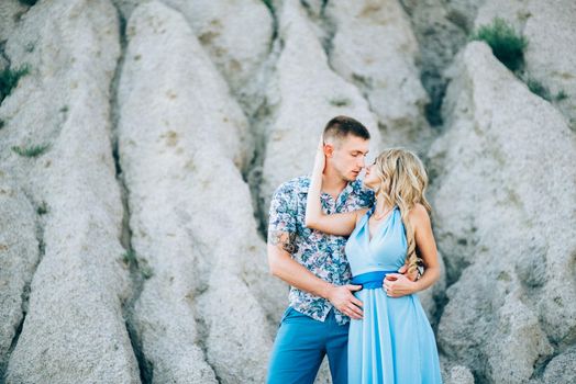 blonde girl in a light blue dress and a guy in a light shorts and short shert in a granite quarry