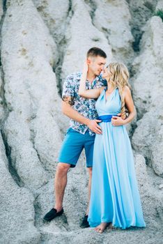 blonde girl in a light blue dress and a guy in a light shorts and short shert in a granite quarry