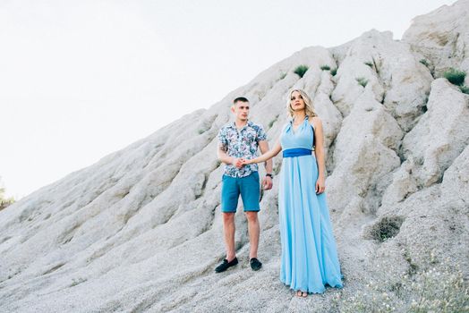 blonde girl in a light blue dress and a guy in a light shorts and short shert in a granite quarry