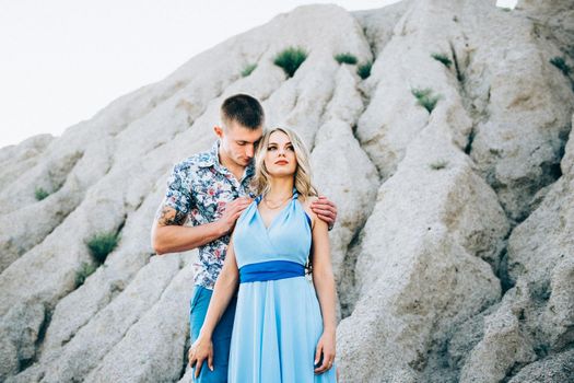 blonde girl in a light blue dress and a guy in a light shorts and short shert in a granite quarry