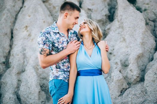 blonde girl in a light blue dress and a guy in a light shorts and short shert in a granite quarry