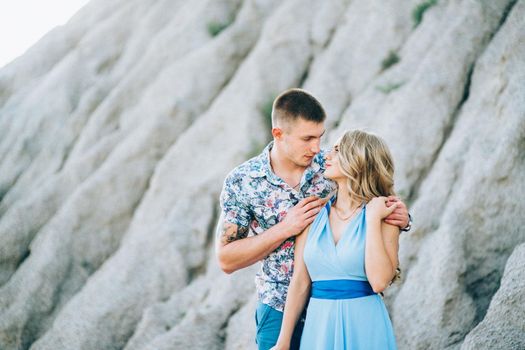 blonde girl in a light blue dress and a guy in a light shorts and short shert in a granite quarry