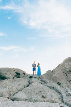 blonde girl in a light blue dress and a guy in a light shorts and short shert in a granite quarry