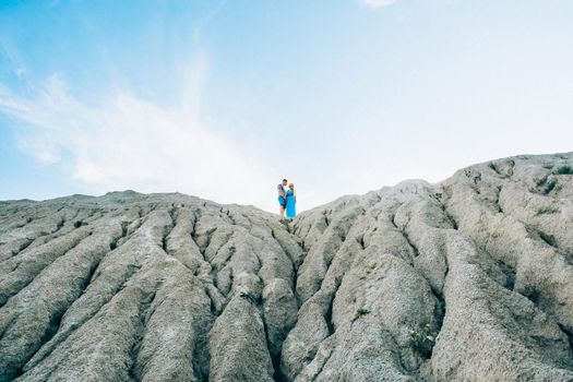 blonde girl in a light blue dress and a guy in a light shorts and short shert in a granite quarry