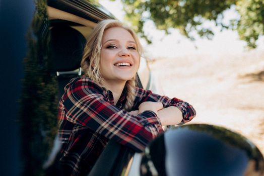 blonde with pigtails in a shirt, jeans, red shoes and black glasses near a white car