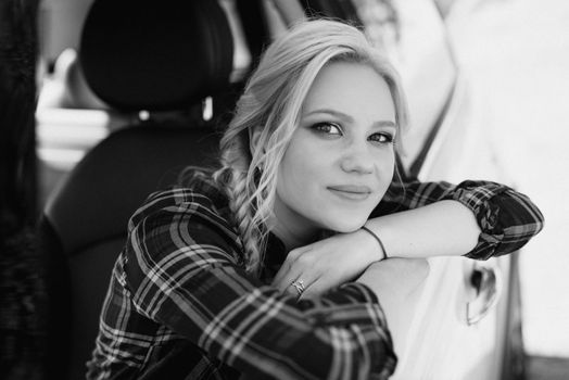 blonde with pigtails in a shirt, jeans, red shoes and black glasses near a white car