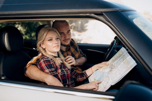 traveling by car of a young couple of a guy and a girl in plaid shirts