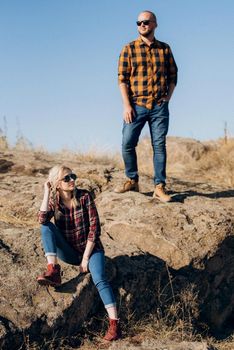 Guy and girl in caged shirts and trekking shoes on granite rocks