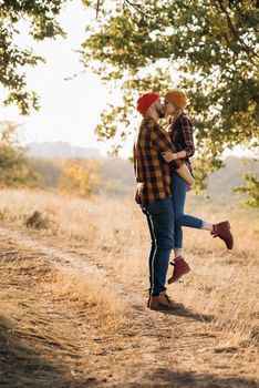 Cheerful guy and girl on a walk in bright knitted hats and plaid shirts