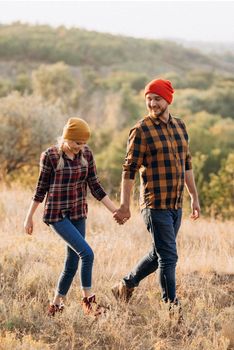 Cheerful guy and girl on a walk in bright knitted hats and plaid shirts
