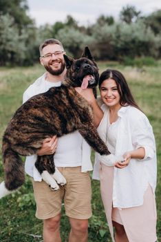 Big dog for a walk with a guy and a girl on the green prairie